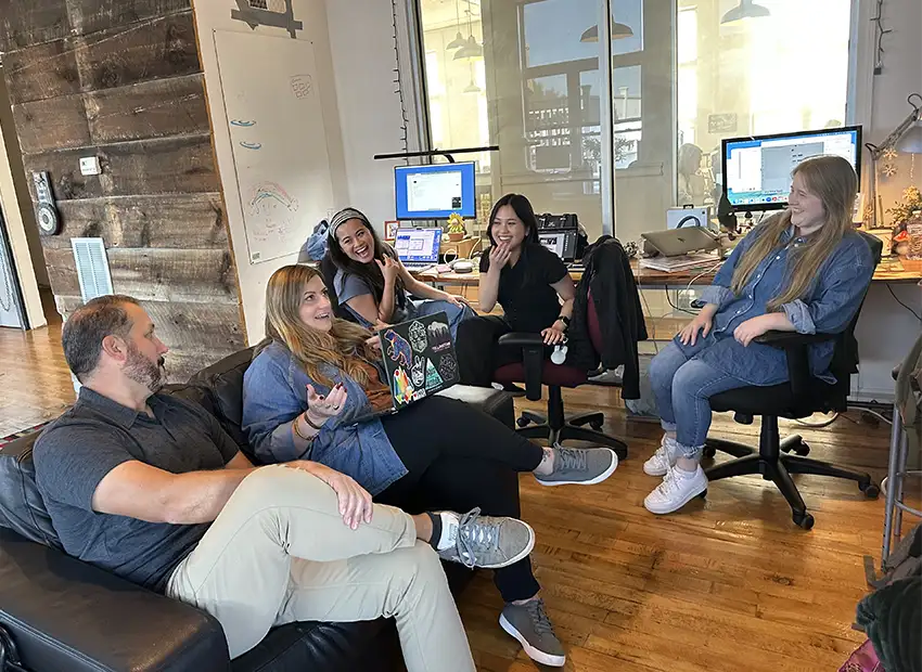 The GO design team sitting in their office laughing and talking