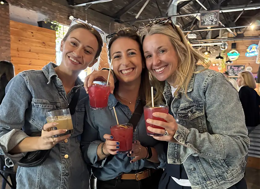 Erin, Kiersten and Adrienne smiling with colorful drinks in-hand